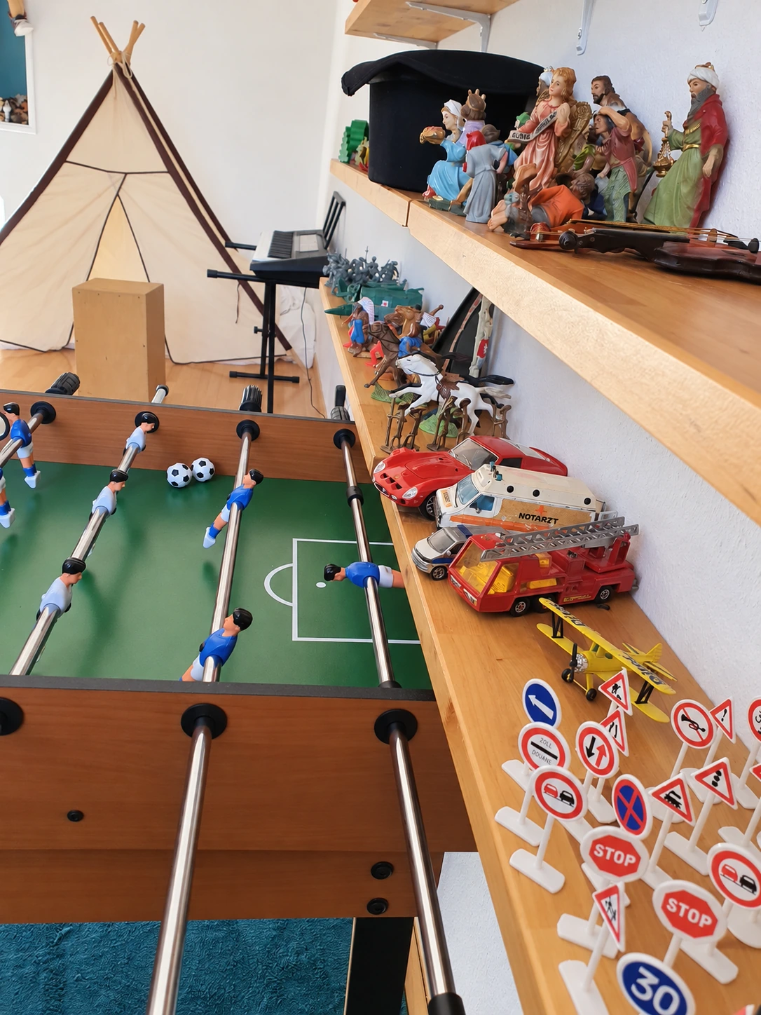 Espace de jeu du cabinet avec baby-foot, étagères de jouets et tipi · Photo du cabinet provenant du site existant · retouchée avec l’IA