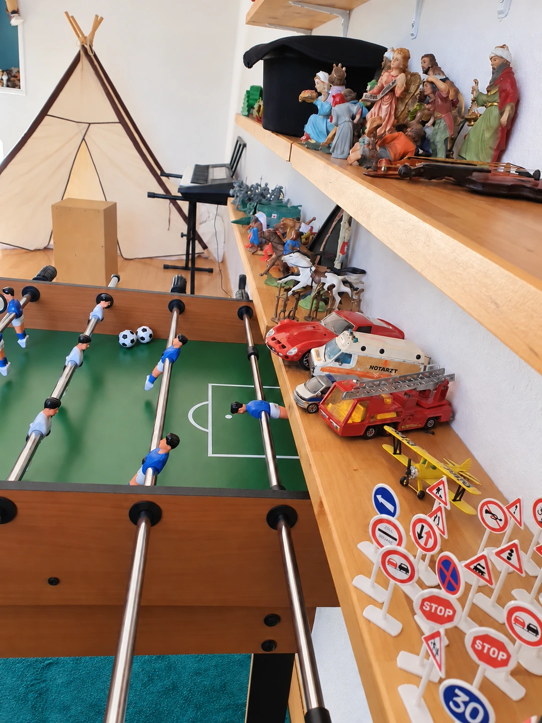 Play room with table football, toy vehicles, figures and a play tent